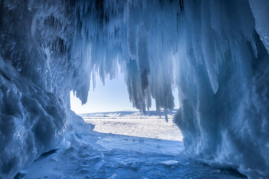 View of Lake Baikal ice cave with hanging icicles and frozen lake surface under bright winter daylight in Irkutsk, Irkutsk Oblast, Russia.