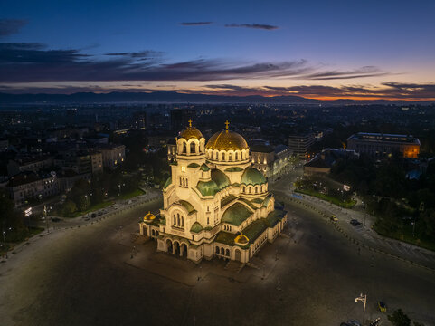 Aerial view of Patriarchal Cathedral St. Alexander Nevsky illuminated at twilight with golden domes and green roofs in the city center of Sofia, Sofia City Province, Bulgaria.