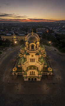 Aerial view of Patriarchal Cathedral St. Alexander Nevsky with its golden domes and green roofs illuminated at sunset in the city center Sofia, Sofia City Province, Bulgaria.