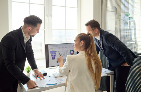 Team analysts in office discussing data dashboard. Three coworkers review charts, plan strategy, evaluate KPIs, and prepare a clear report for management. Concept is business data analytics.