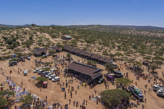Aerial view of the bustling outdoor market with numerous stalls, vehicles, and people gathered in the arid landscape of Oldonyiro, Isiolo County, Kenya.