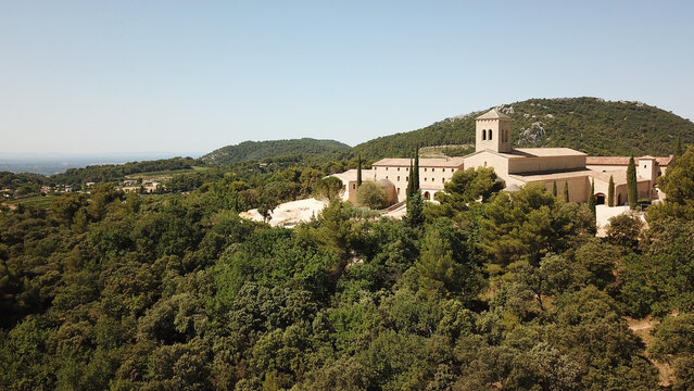 Aerial view of Abbaye Sainte-Madeleine surrounded by dense forest and rolling hills in Le Barroux, Provence-Alpes-Cote d'Azur, France.