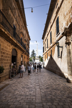 Ciutadella, Balearic Islands, Spain - 26 June 2026: View of the historic obelisk in Placa des Born surrounded by traditional stone buildings and people walking along the cobblestone street.