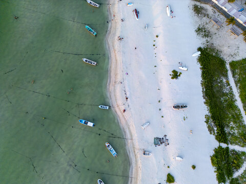 Aerial view of Playa Puerto Progreso with small boats anchored in the turquoise water along the white sandy beach and coastal vegetation in Yucatan, Mexico.