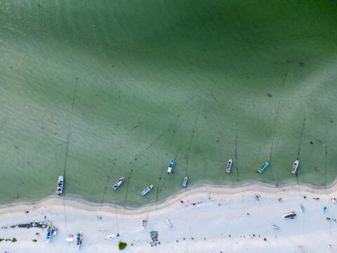 Aerial view of Playa Puerto Progreso with small fishing boats moored in shallow turquoise water along the white sandy beach in Yucatan, Mexico.