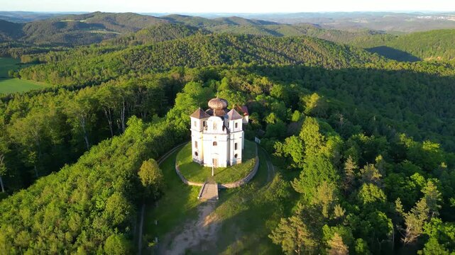 Aerial view of Makova hora church surrounded by dense green forest on a hill in Smolotely, Stredocesky kraj, Czechia.