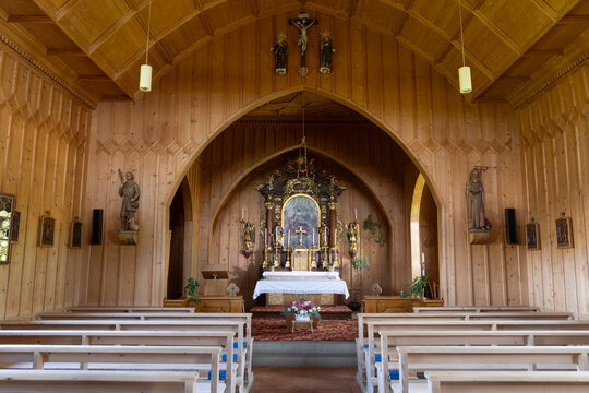 View of the interior of the chapel in Stoos with wooden walls, pews, and an ornate altar in Schwyz, Schwyz, Switzerland.