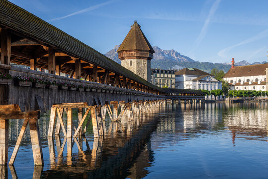 View of the historic Chapel Bridge spanning the Reuss River with the Wasserturm tower and mountains in the background in Lucerne, Lucerne, Switzerland.