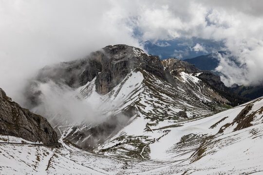 View of the snow-covered rocky peaks of Mount Pilatus partially obscured by clouds in the Swiss Alps in Alpnach, Obwalden, Switzerland.