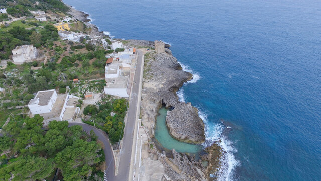 Aerial view of the natural pool and historic watchtower along the rocky coastline in Marina Serra, Puglia, Italy.