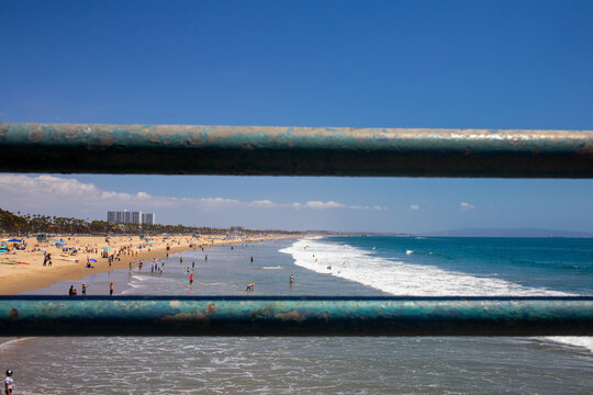 Santa Monica, California, United States - 29 June 2026: View of Santa Monica Pier overlooking the sandy beach with people swimming and relaxing under a clear blue sky.