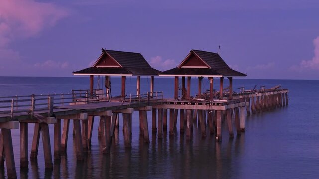 Aerial view of Naples Pier with wooden structures extending into the calm ocean under a purple twilight sky in Naples, Florida, United States.