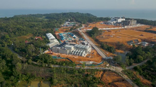 Aerial view of Data Center Nongsa construction site with industrial buildings and earthworks surrounded by lush greenery and coastal landscape in Batam, Riau Islands, Indonesia.