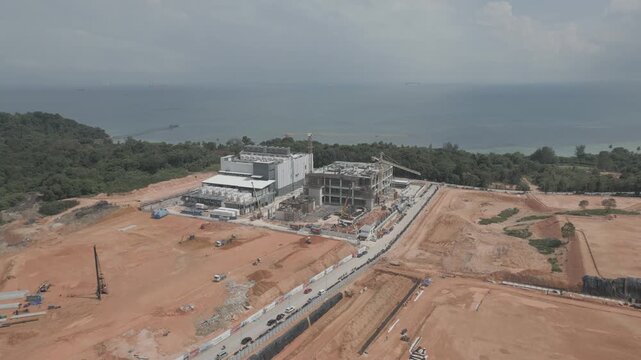 Aerial view of Data Center Nongsa construction site with industrial buildings, cranes, and cleared land near the coastline in Batam, Riau Islands, Indonesia.