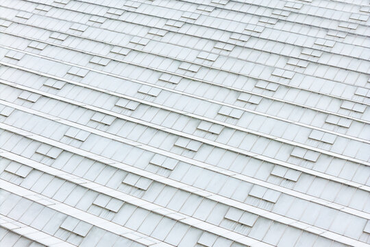 Aerial view of a large greenhouse roof with repeating glass panels and ventilation hatches used for food production in Poland.