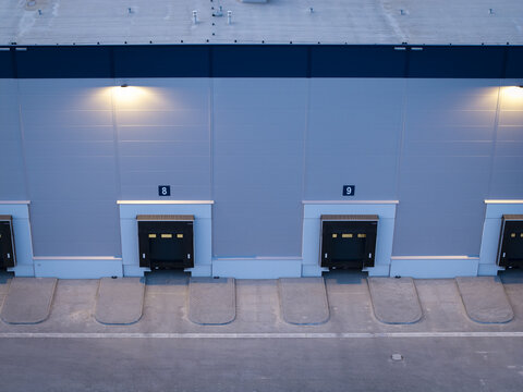 Aerial view of a modern logistics warehouse with loading docks numbered eight and nine illuminated by exterior wall lights in Krakow, Lesser Poland Voivode, Poland.