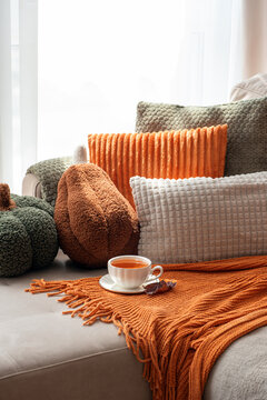 Cozy autumn still life with pumpkins, pillows, and warm tea on a couch