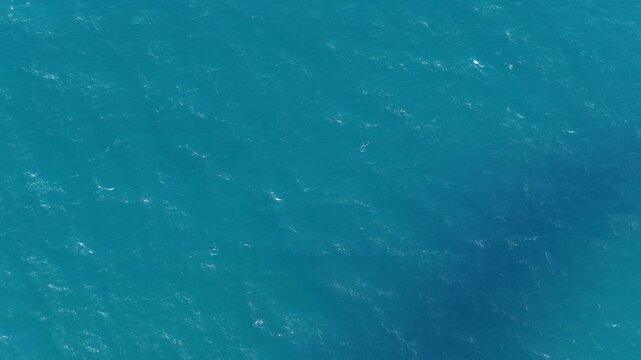 Aerial view of the clear turquoise sea with gentle ripples and deep blue water patterns in Karimunjawa, Central Java, Indonesia.