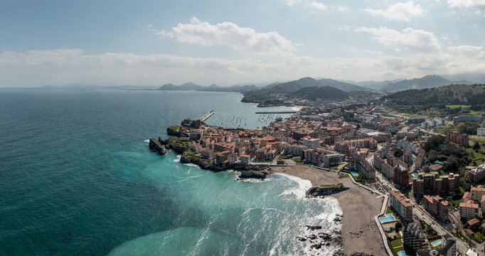 Aerial view of the historic town of Castro Urdiales featuring its harbor, sandy beach, and coastal architecture along the Cantabrian Sea in Castro Urdiales, Cantabria, Spain.