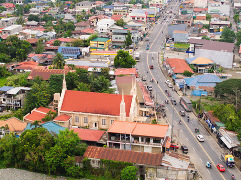 Aerial view of the Iglesia Ni Cristo church with its red roof and spires, located near a busy road and residential buildings in Bambang, Cagayan Valley, Philippines.