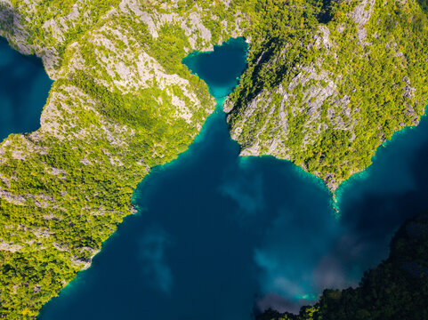 Aerial view of Barracuda Lake in the Coron Island Protected Area, featuring deep blue waters surrounded by lush green limestone cliffs in Coron, Mimaropa, Philippines.