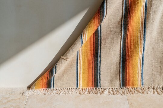 Striped woven serape blanket draped in a diagonal fold with warm sunshine and copy space for textile presentation and cultural design campaigns