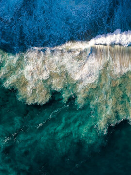 Aerial view of turquoise ocean waves crashing against the shore at Sandpatch, Western Australia, Australia.