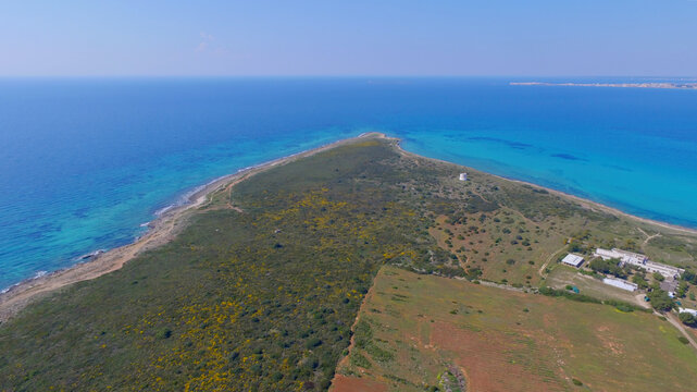 Aerial view of Punta Pizzo with its coastal scrubland, turquoise waters, and historic tower in Gallipoli, Apulia, Italy.