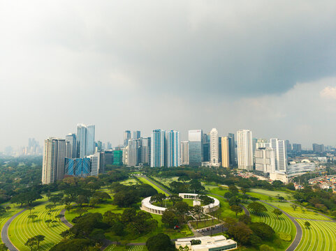Aerial view of Manila American Cemetery and Memorial with its circular structure and green lawns, set against the modern high-rise skyline of Makati City, Metro Manila, Philippines.