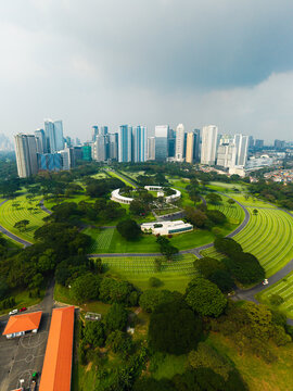 Aerial view of Manila American Cemetery and Memorial with its circular layout and rows of white crosses set against the modern high-rise skyline of Makati City, Metro Manila, Philippines.