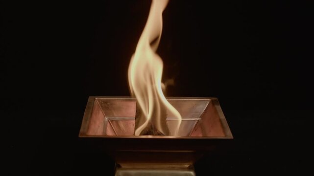 Ceremonial ritual fire in Havan kund, container, copper bowl, pot, vessel on black background. Fire ritual in Hindu tradition in the havan pot, divine flames burning in the copper brass, occult, magic
