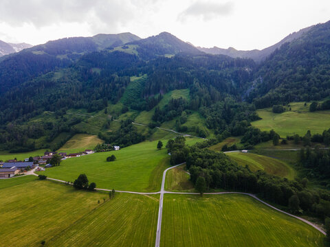 Aerial view of lush green meadows, winding country roads, and dense forests in Fusch an der Grossglocknerstrasse, Salzburg, Austria.