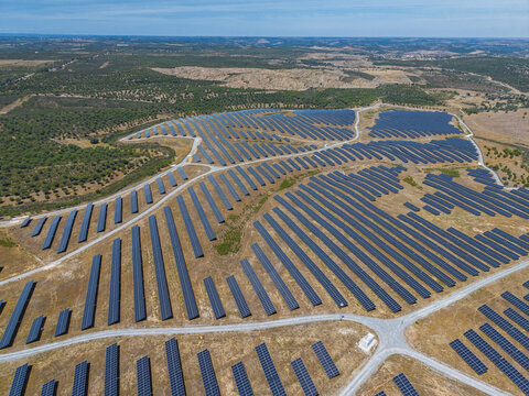 Aerial view of a large solar farm with rows of photovoltaic panels installed on dry rural terrain in Gioes, Faro, Portugal.