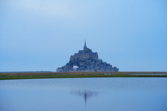 View of the historic Mont Saint-Michel abbey rising above the calm tidal waters in Mont Saint-Michel, Normandy, France.