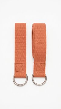 Two terracotta cotton yoga straps with metal d-rings on white background. Essential equipment for flexibility and stretching. Ideal for fitness product catalogs or health blogs.