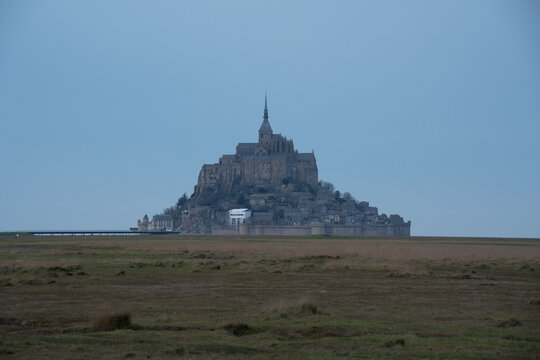View of the historic Mont Saint-Michel abbey rising above the tidal flats in the soft light of dawn in Mont Saint-Michel, Normandy, France.
