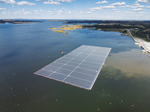 Aerial view of the floating solar farm on the Barragem de Alqueva reservoir with blue water and surrounding landscape in Moura, Distrito de Evora, Portugal.