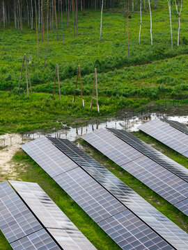 Aerial view of solar panels installed in a green field near a forest in Suntazi, Ogre Municipality, Latvia.