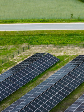 Aerial view of solar panels arranged in rows on a grassy field next to a road in the countryside in Suntazi, Ogre Municipality, Latvia.