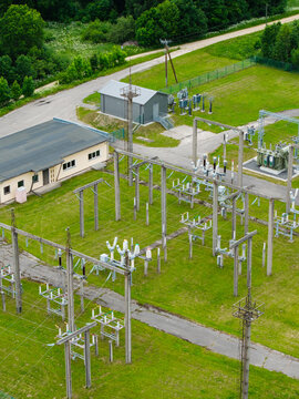 Aerial view of an electrical substation featuring power lines, transformers, and a small utility building surrounded by green grass in Suntazi, Ogre Municipality, Latvia.
