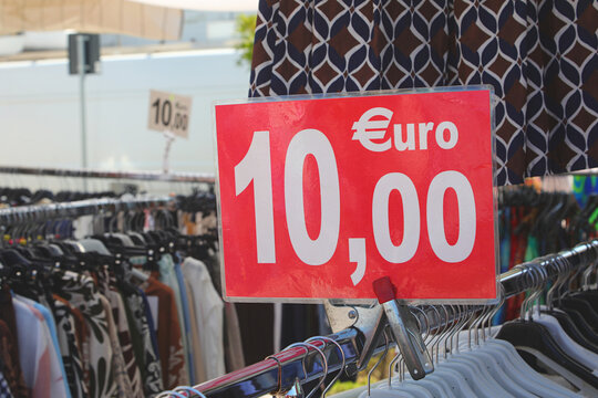 Red price sign showing ten euro price tag attached to clothing rack at outdoor street market