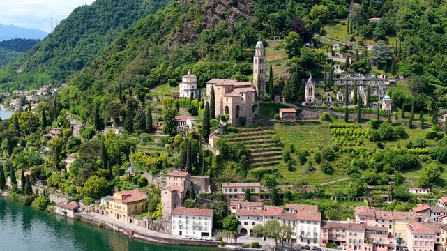 Aerial view of Morcote village with the church of Santa Maria del Sasso, terraced gardens, and historic buildings along the shores of Lake Lugano, Lugano, Ticino, Switzerland.