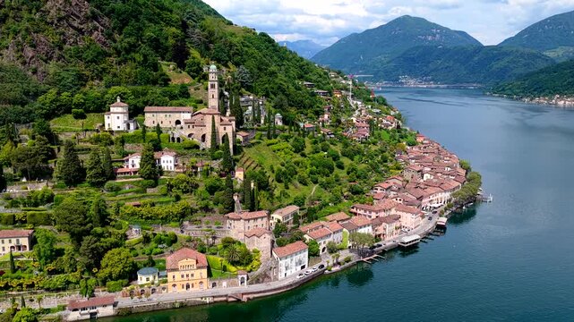 Aerial view of the historic village of Morcote with its iconic church bell tower and terraced houses along the shores of Lake Lugano in Lugano, Ticino, Switzerland.