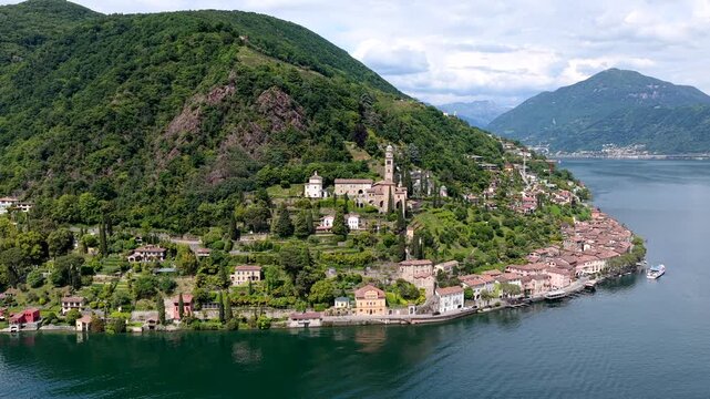 Aerial view of the historic village of Morcote nestled on the shores of Lake Lugano with lush green hills and traditional architecture in Lugano, Ticino, Switzerland.