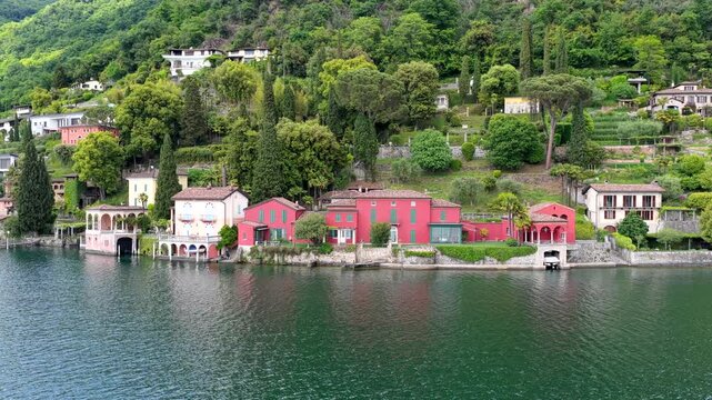 Aerial view of Morcote village on Lake Lugano, featuring colorful historic houses, lush green hills, and dense vegetation in Lugano, Ticino, Switzerland.