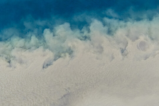 Aerial view of glacial sediment flowing into the deep blue ocean, creating a striking contrast between the milky white silt and the dark sea water, Vik, Myrdalshreppur, Iceland.