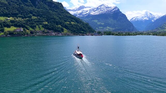 Aerial view of a historic paddle steamer cruising on Lake Lucerne with snow-capped mountains in the background in Fluelen, Uri, Switzerland.