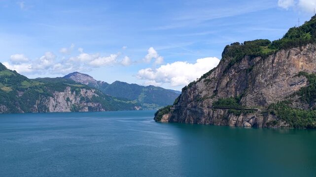 Aerial view of Lake Lucerne surrounded by steep mountains and cliffs under a clear blue sky in Fluelen, Uri, Switzerland.
