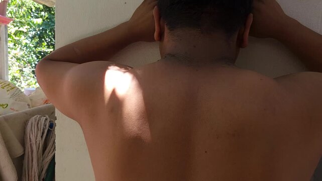 Back View of Young Man Leaning on Wall Showing Neck Skin Tags