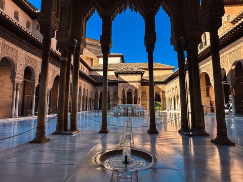 View of the Court of the Lions at the Alhambra, featuring intricate Moorish arches, marble columns, and the iconic central fountain in Granada, Andalucia, Spain.